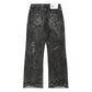 Distressed black denim jeans with a relaxed, bootcut fit . The jeans feature a heavily worn aesthetic, including brown splatter-style detailing, embroidery on both back pockets and frayed hems. 