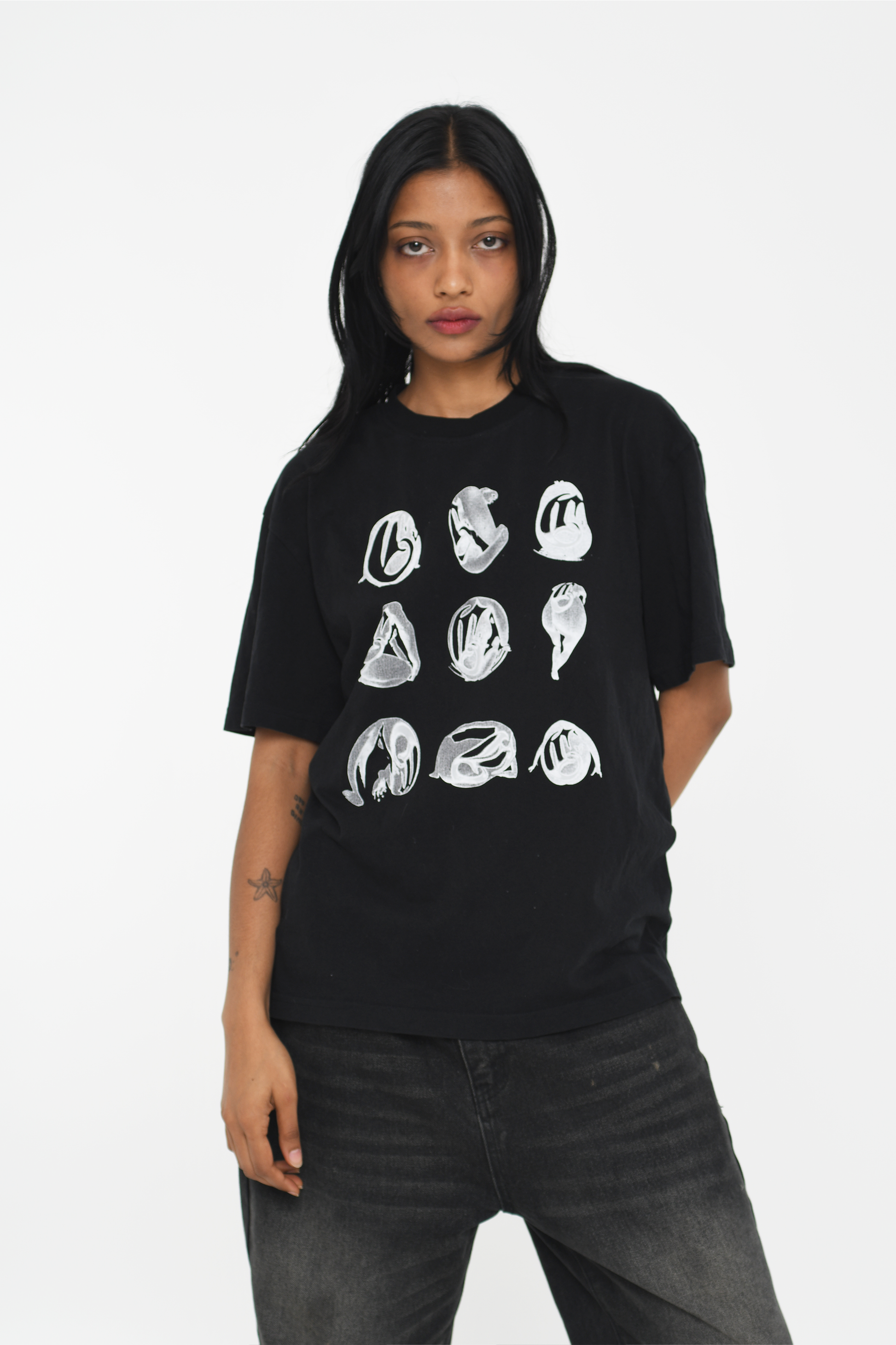 Female model wearing a black cotton T-shirt featuring a white abstract graphic design, styled for a casual, modern look.