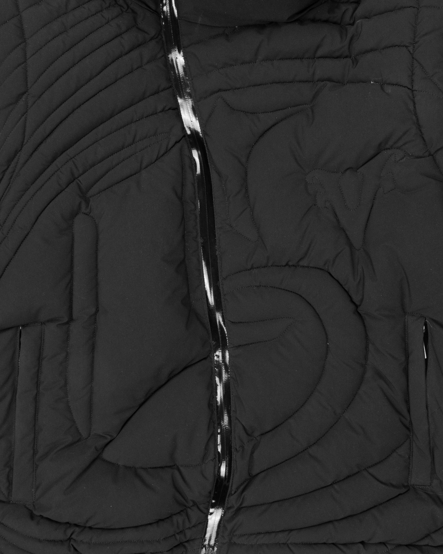 Close-up of a black embossed puffer jacket showcasing the intricate quilted pattern and glossy asymmetrical zipper detail, highlighting its modern design.