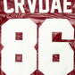 Close-up detail of the CRVDAE and 86 design on the back of a burgundy faux leather jacket, showcasing bold white lettering on a shiny finish.